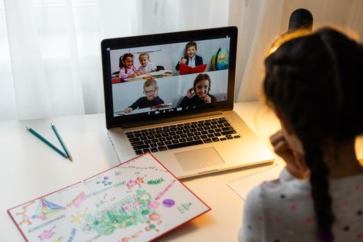 Happy little girl at home working with a laptop