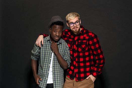 Studio lifestyle portrait of two best friends hipster boys going crazy and having great time together. On black background. Belt portrait