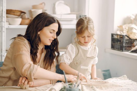 Woman and girl kneading clay. Family make art product at table in pottery workshop. Mother with daughter.