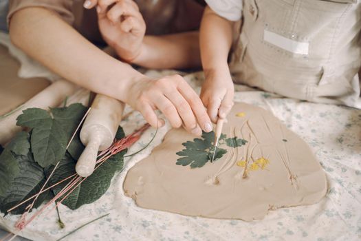 Woman and girl kneading clay. Family make art product at table in pottery workshop. Mother with daughter.