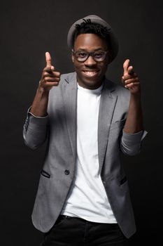 Portrait of a fashionable african american man smiling on black background. A nice guy in a gray jacket and a white T-shirt on a dark studio background. Belt portrait