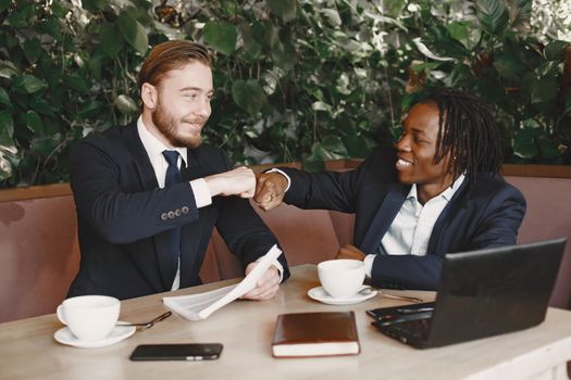 African man. Guy in a black suit. Mixed people have a metting at the cafe.