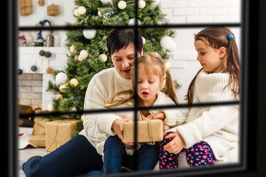 Big family with three children celebrating Christmas at home. Festive dinner at fireplace and Xmas tree. Parent and kids eating at fire place in decorated room. Child lighting advent wreath candle