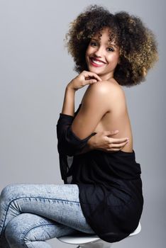 Young black woman with afro hairstyle laughing. Girl wearing black clothes. Studio shot.