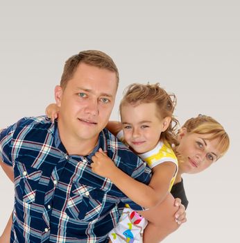 Portrait of happy family of three. Happy mother and daughter peeking from behind dad. close-up.On a gray background.