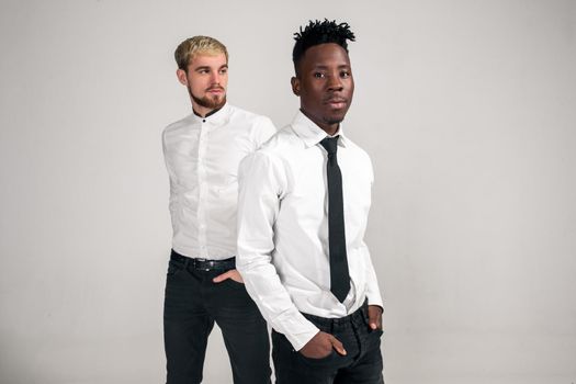 Friends. Two guys in white shirts and dark pants posing in the studio on a white background. Copy space. Belt portrait