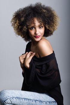 Sexy black woman with afro hairstyle. Girl wearing black shirt and blue jeans. Studio shot.