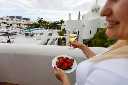 Woman eating a fresh red strawberries outdoors on the balcony.