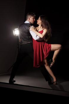 Man and woman in the most romantic dance tango over dark background