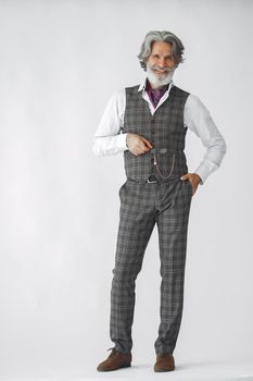 Close up portrait of grinning old-fashioned man. Elegant man in a studio. Grandfather with a clock.