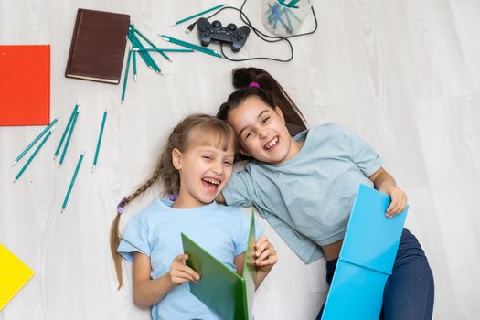 two little girls sisters reading a book lying on the floor