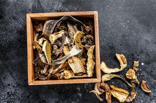 Boletus wild dried mushrooms in a wooden box. Black background. Top view.