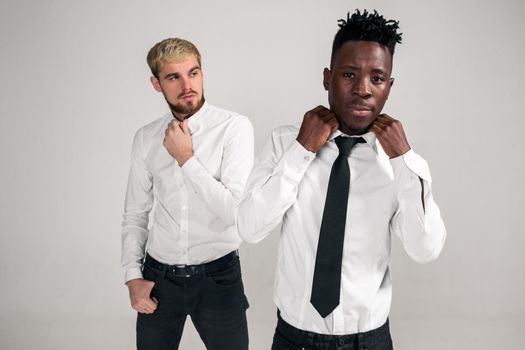 Friends. Two guys in white shirts and dark pants posing in the studio on a white background. Copy space. Belt portrait