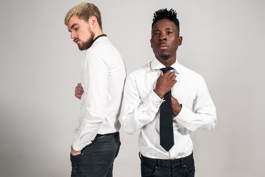 Friends. Two guys in white shirts and dark pants posing in the studio on a white background. Copy space. Belt portrait