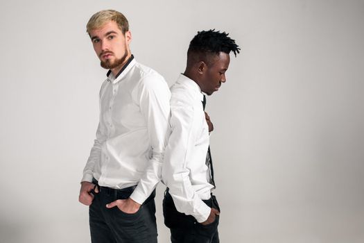 Friends. Two guys in white shirts and dark pants posing in the studio on a white background. Copy space. Belt portrait