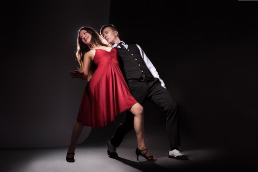 Man and woman in the most romantic dance tango over dark background