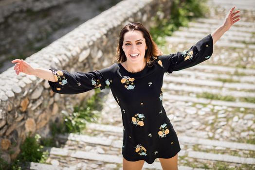 Middle-aged woman, with open arms, enjoying the sunlight in an old neighborhood of Granada in summer