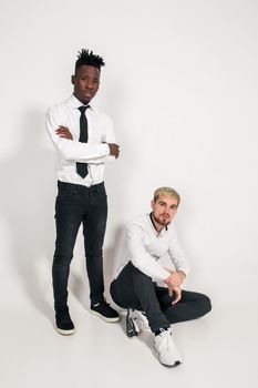 Friends. Two guys in white shirts and dark pants posing in the studio on a white background. Copy space. Full-length photo