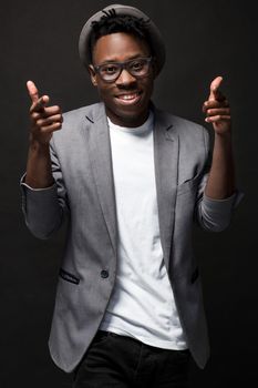 Portrait of a fashionable african american man smiling on black background. A nice guy in a gray jacket and a white T-shirt on a dark studio background. Belt portrait