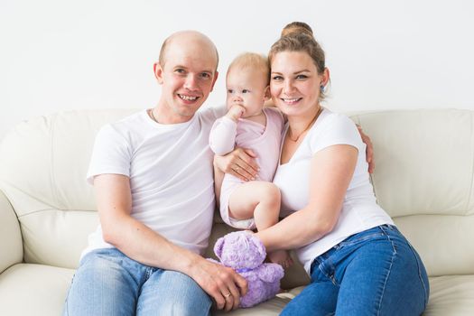 Smiling mother and father holding their newborn baby daughter at home