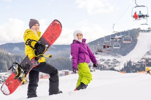 mother and daughter with snowboards in a mountain resort