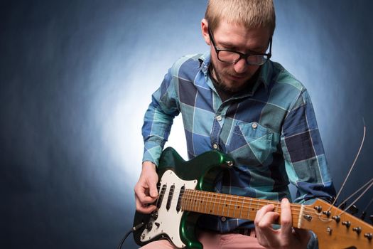 man playing electrical guitar on dark background