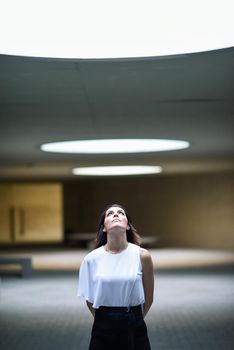 Beautiful brunette woman, model of fashion, posing in modern building with casual clothes.