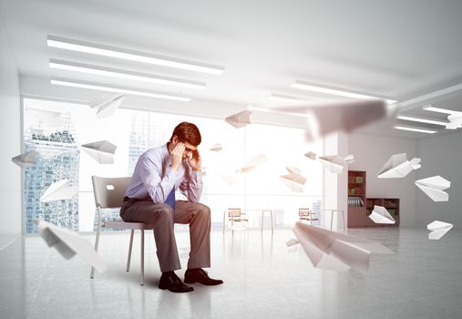 young businessman sitting on a chair with his head in his hands