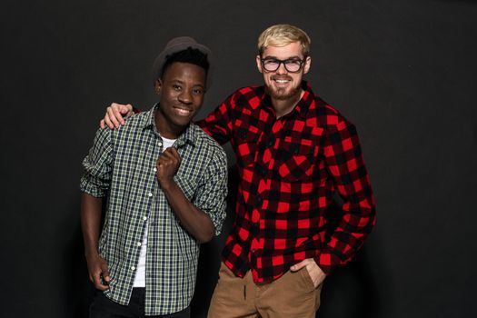 Studio lifestyle portrait of two best friends hipster boys going crazy and having great time together. On black background. Belt portrait