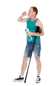 Man in t-shirt and shorts, with sticks for Nordic walking, drinking water from a glass -Isolated on white background