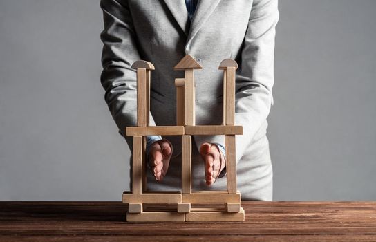 Business woman building construction on table from wooden blocks. Strategy planning and company development. Young woman wearing formal wear sitting in office interior. Business motivation concept