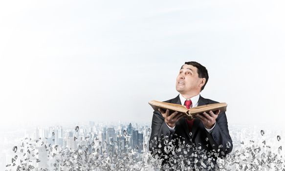 Happy businessman holding open old book. Smiling man in suit standing on city background with flying around various letters. Bookkeeper holding accountant book. Business accounting and consulting