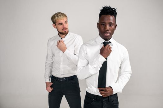 Friends. Two guys in white shirts and dark pants posing in the studio on a white background. Copy space. Belt portrait