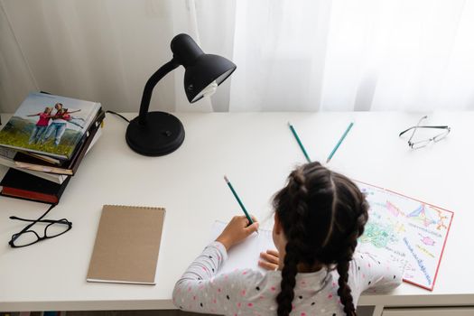 children, education and learning concept - student girl with book writing to notebook at home
