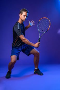 Young tennis player in action against purple background, full length portrait