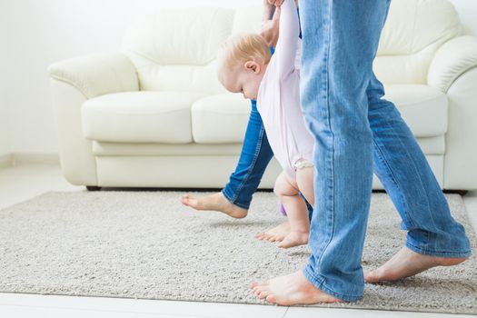 First steps of baby toddler learning to walk in white sunny living room. Footwear for child