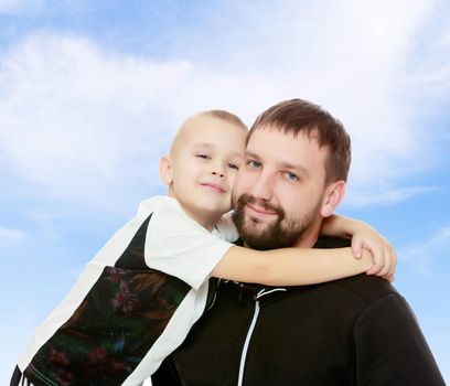 Happy family. Dad and son hug each other.On the background of summer blue sky and fluffy clouds.