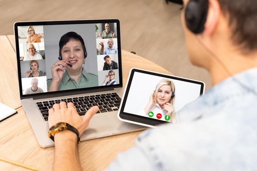 View over businessman shoulder at laptop where four multiracial colleagues engaged at group meeting on-line, video conference call communicating by webcam, distant webinar, online negotiations concept