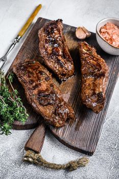 Grilled brisket steaks in bbq sauce on a wooden board. White background. Top view.