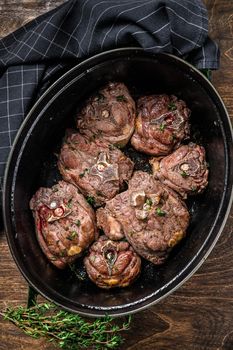 Stewed lamb neck meat in a pan with herbs. wooden background. Top view.