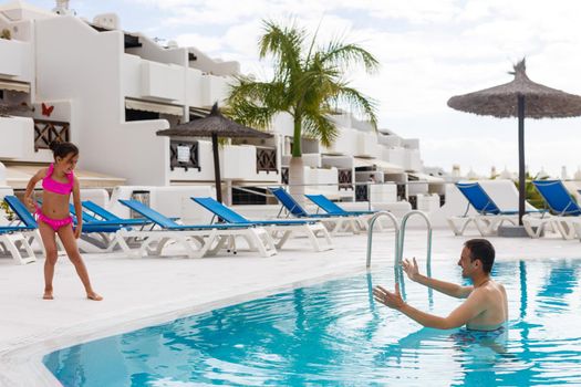 Father playing with his daughter in swimming pool.