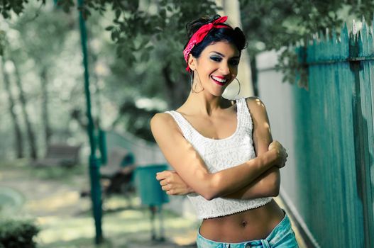 Portrait of a pin-up girl. American style, in a garden, wearing jeans and t-shirt