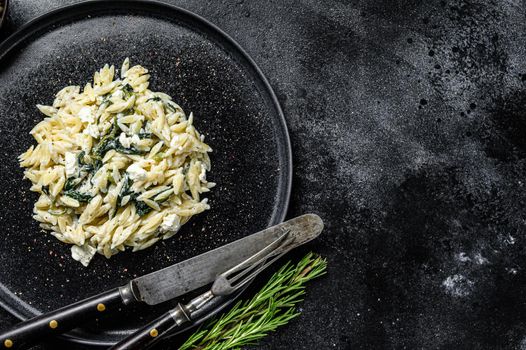 Homemade spinach orzo pasta on a plate. Black background. Top view. Copy space.