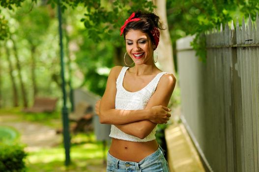Portrait of a pin-up girl. American style, in a garden, wearing jeans and t-shirt