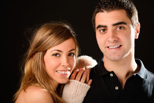 Portrait of a happy couple smiling at camera on black background