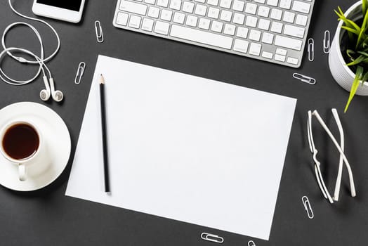 Top view of modern workplace with blank paper sheet. Flat lay black surface with smartphone, notepad and cup of coffee. Top view office workspace and freelance. Digital technology and mobile lifestyle