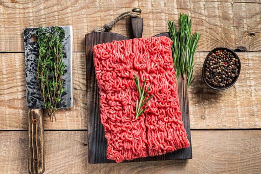 Fresh Raw mince beef meat on a butcher cutting board with cleaver. Wooden background. Top view.