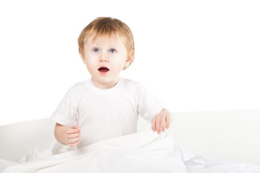 cute excited baby girl in bed at home over white