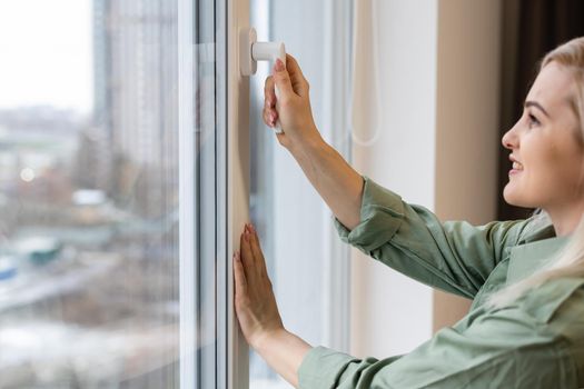 Happy young woman stand near window breathe fresh air stretch exercise in bedroom, smiling millennial girl overjoyed welcome new sunny morning at home or hotel, optimism, happiness concept