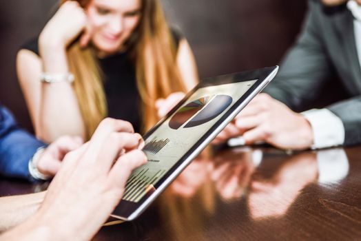 Close-up of a modern business team using tablet computer to work with financial data